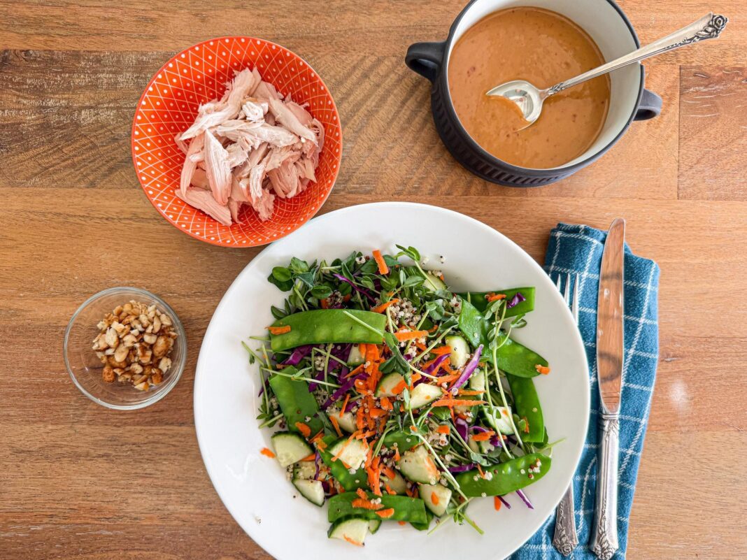 thai chicken and quinoa salad with pea shoots and peanut dressing plated