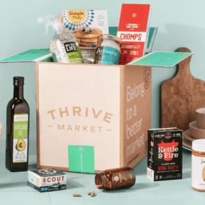 A cardboard box labeled Thrive Market, with non-perishable snacks and groceries in and around it