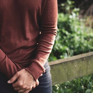 A man wears a rust-colored, long-sleeved merino wool shirt from Nui.