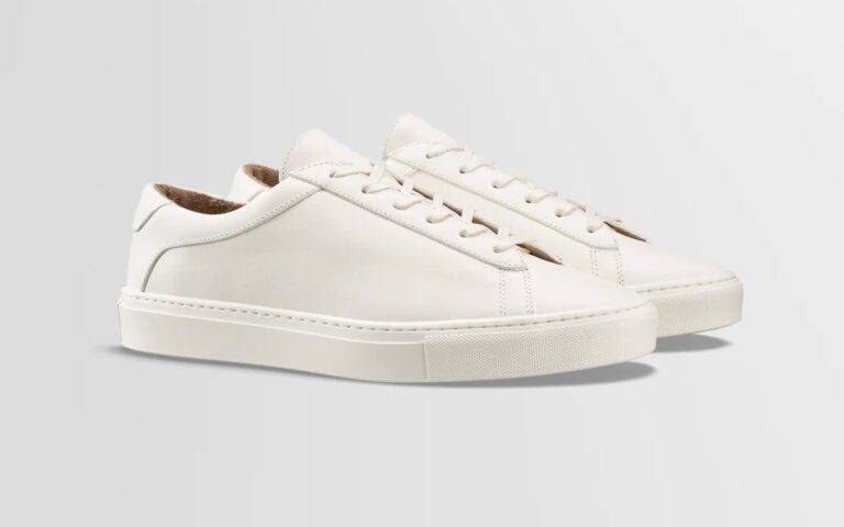 A pair of sleek, creamy white tennis shoes with white outsoles and white laces made by Italian brand Koio.