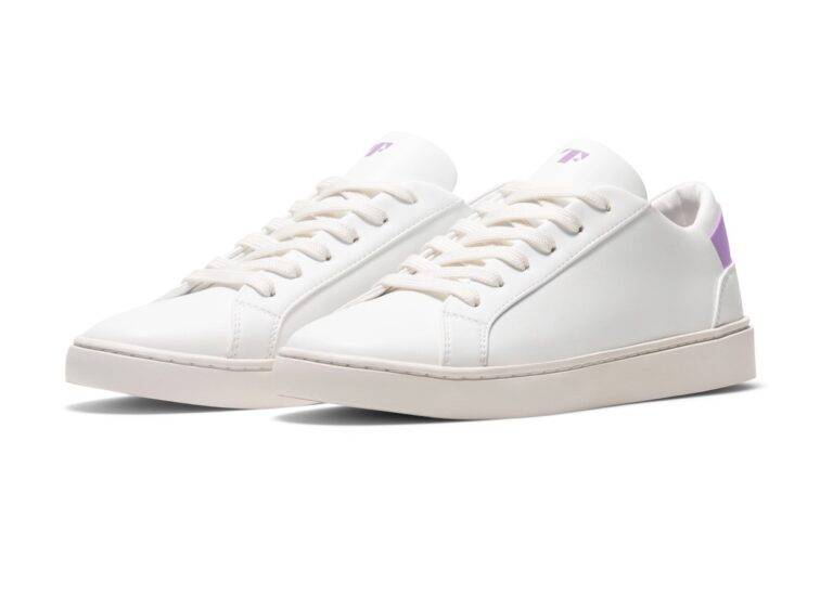 Simple white tennis shoes from vegan brand Thousand Fell that look like white leather. The shoes have a bright lavender accent on the back heel.