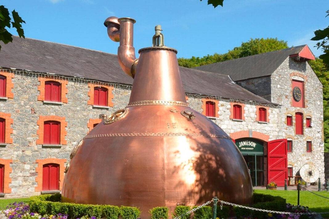 Exterior of Midleton Distillery with large ornamental pot still in foreground.
