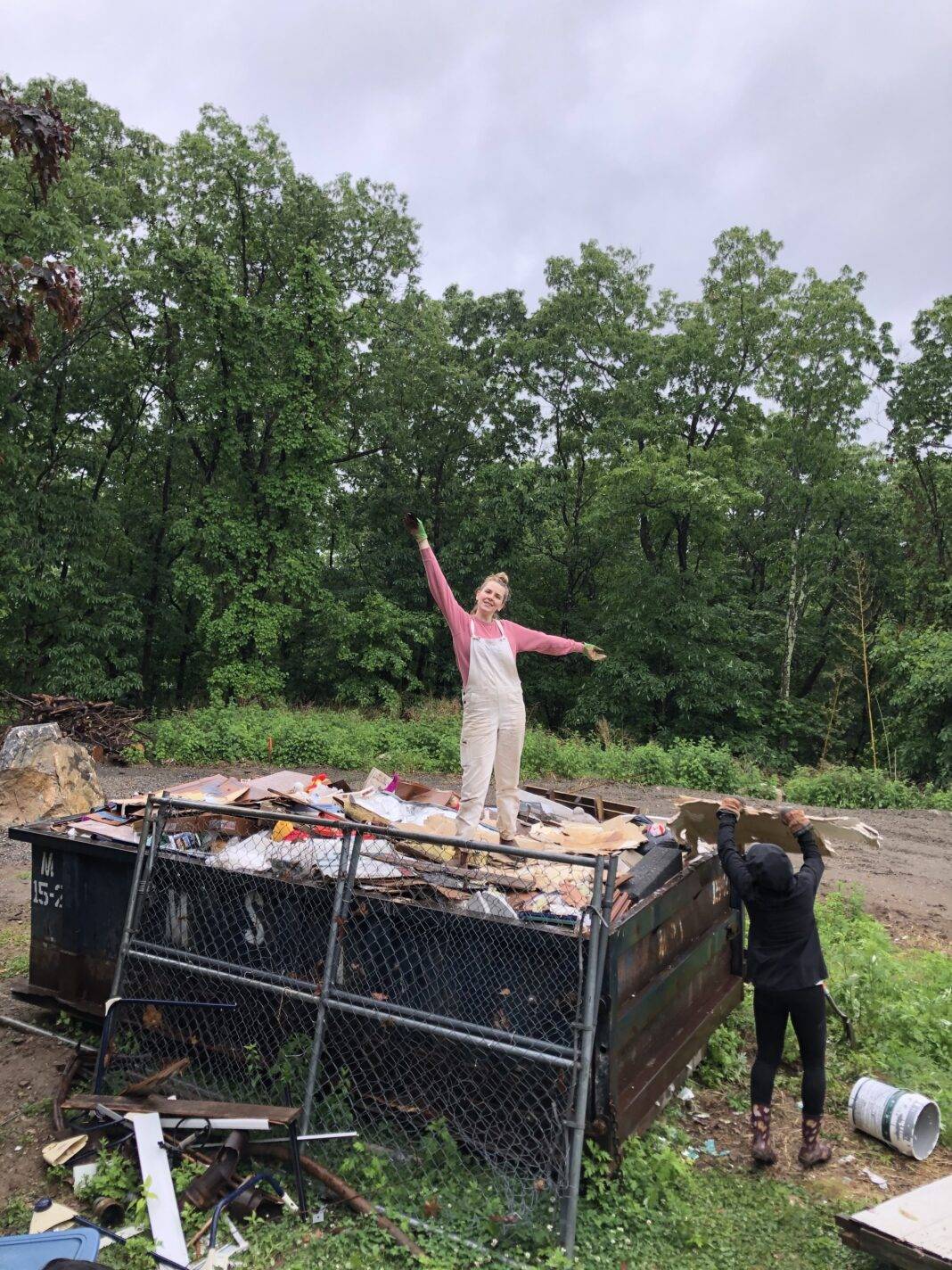 Bea stands atop a dumpster full of demolition detritus.