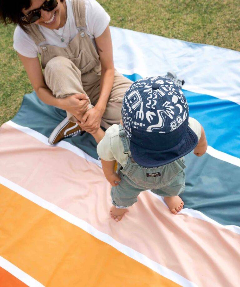 A woman and toddler on a striped picnic blanket
