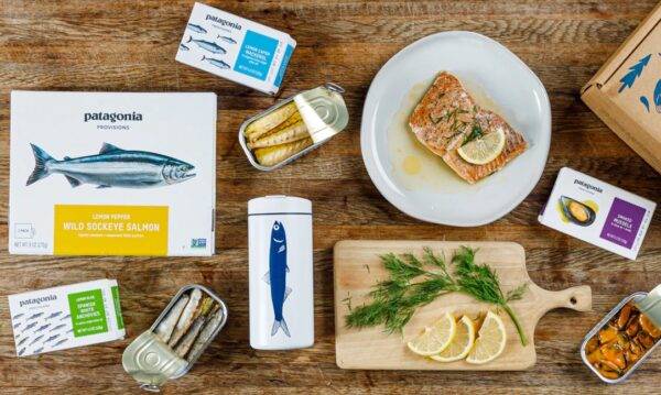 An assortment of food items on a wood board, including sardines, mussels, and salmon..