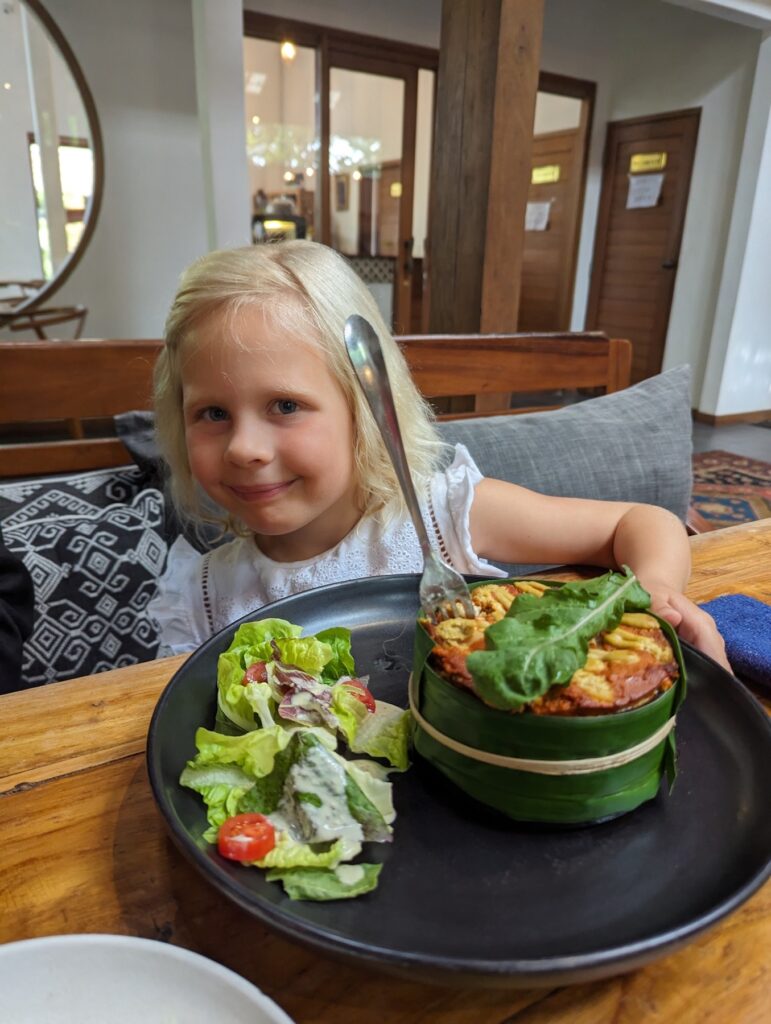 young girls with banana leaf bowl and salad