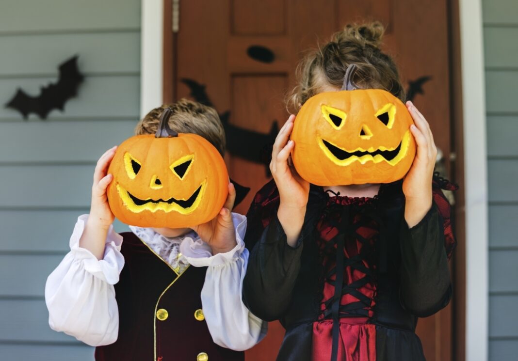 two kids holding jack o lanterns in front of faces