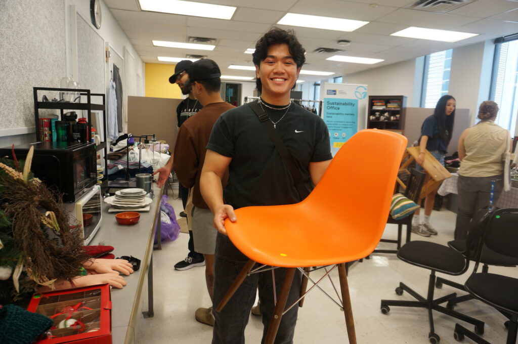 student holding orange chair in free store