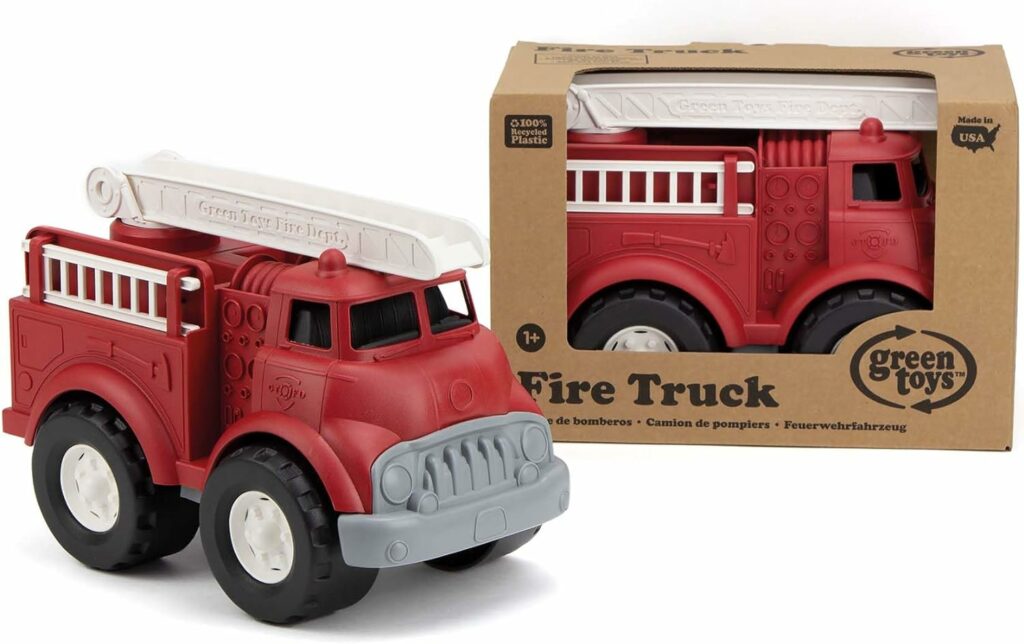 A plastic fire truck toy next to a plastic fire truck boy in a brown paper box with the words Green Toys Fire truck printed on the box.  
