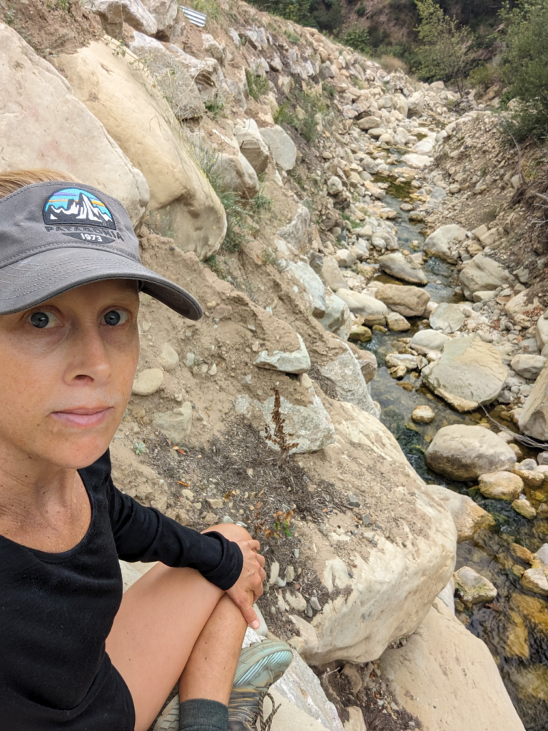 Lizzy Fallows sits alongside a creek