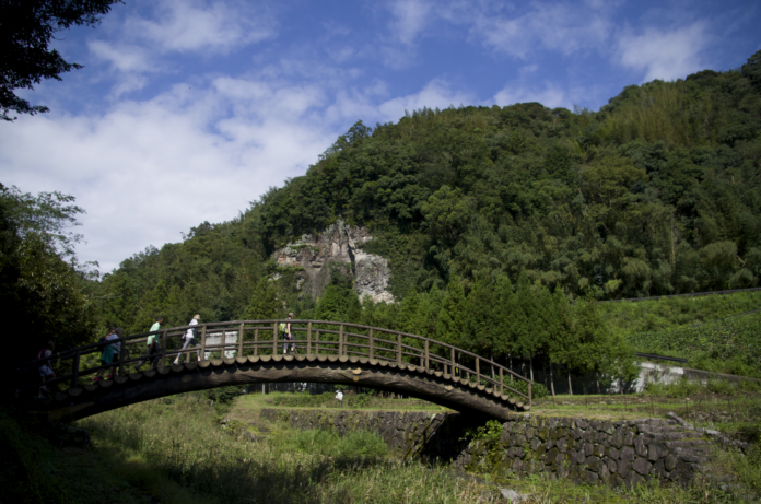 crossing-the-bridge-on-kunisaki-yufuin-walk People walking across a bridge.
