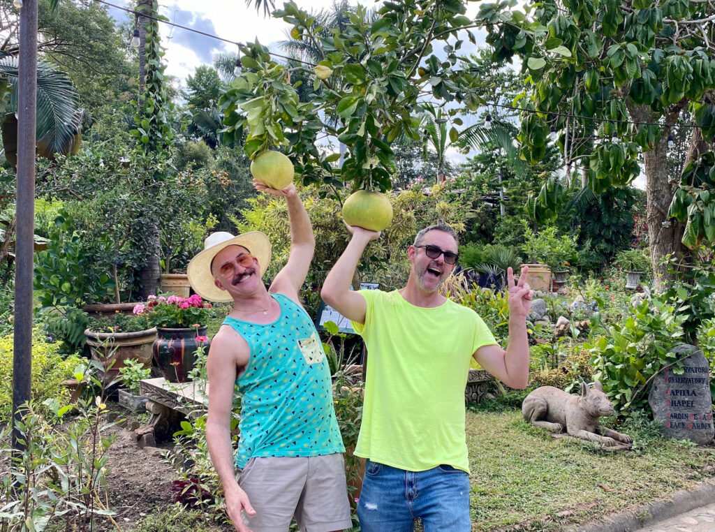 David Allen Burns and Austin Young holding fruit in botantical garden