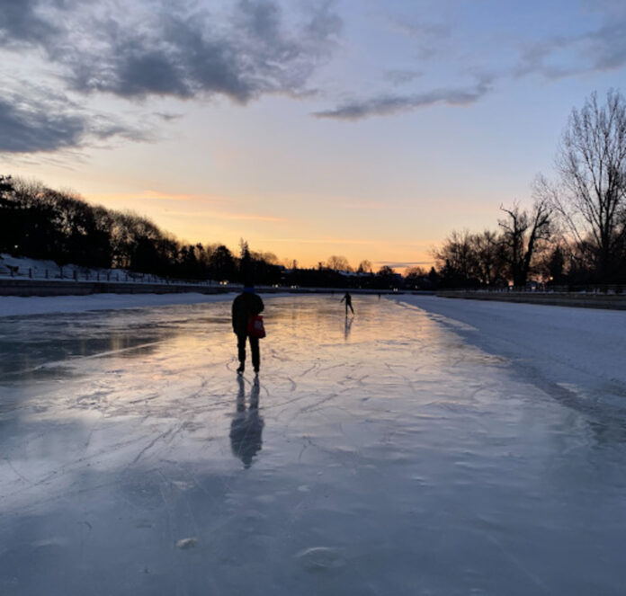 skater on ice pond at sunset