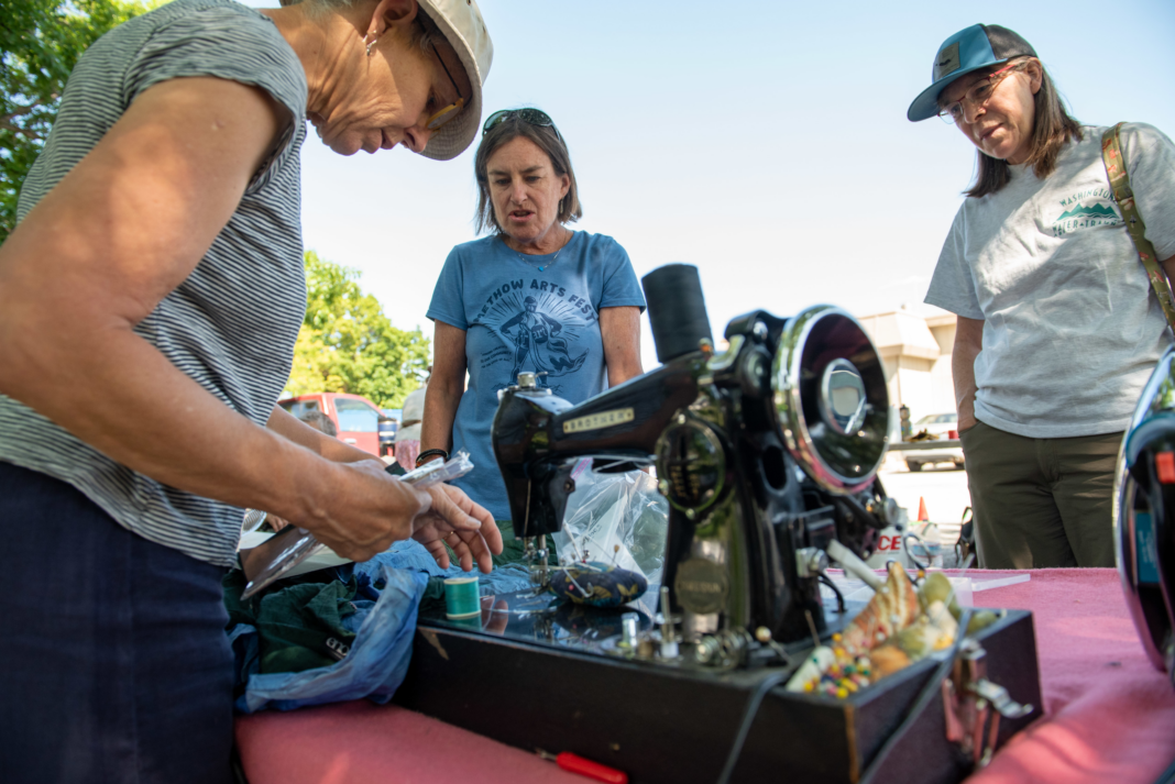 Volunteers gather around a sewing machine.