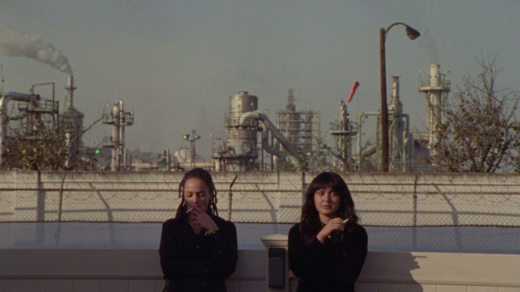 two young people in front of coal plant with cigarettes