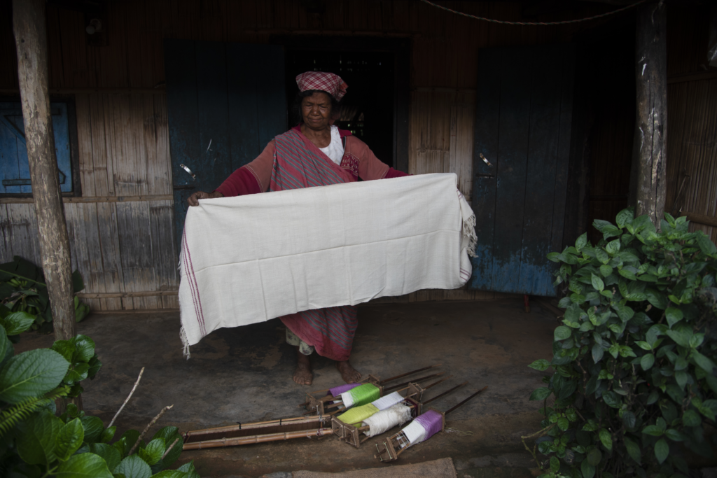 A woman displaying her undyed, handspun eri silk fabric.