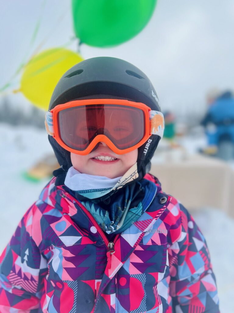 child in goggles and snowsuit