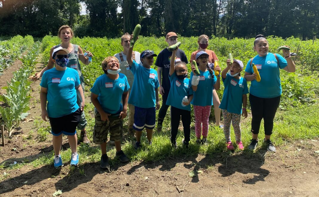 group of students holding vegetables on a farm