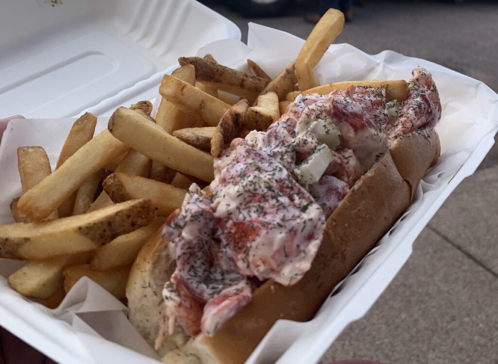 lobster roll with french fries in takeout container