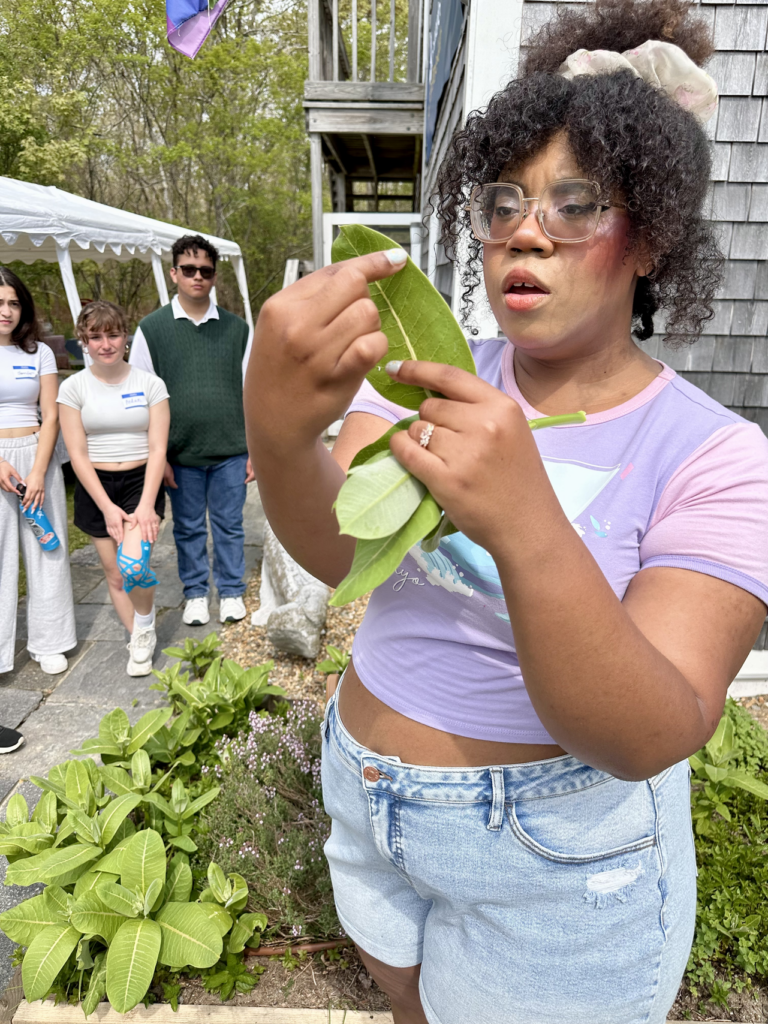 A woman holds a milkweed plant.