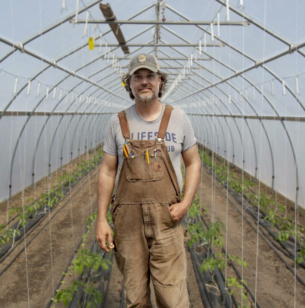 A man stands in a greenhouse.
