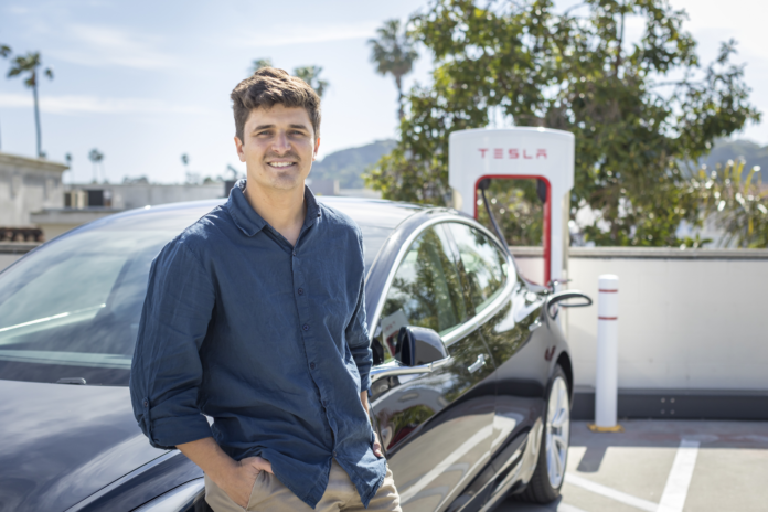 Man leaning on his car at a Tesla charging station
