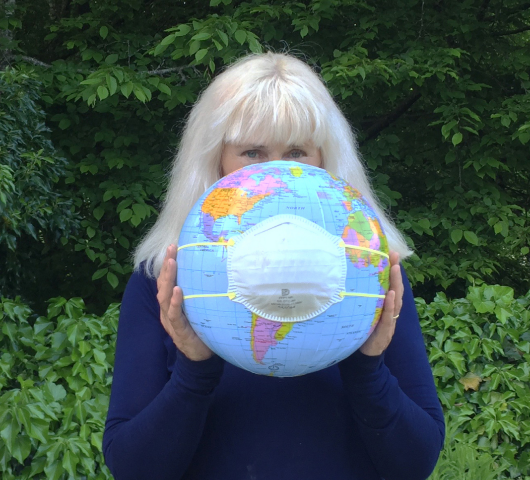 Artist Gloria Friedmann holding a globe with a mask on it.