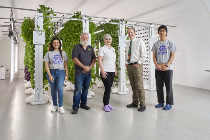 five people standing in front of vertical garden