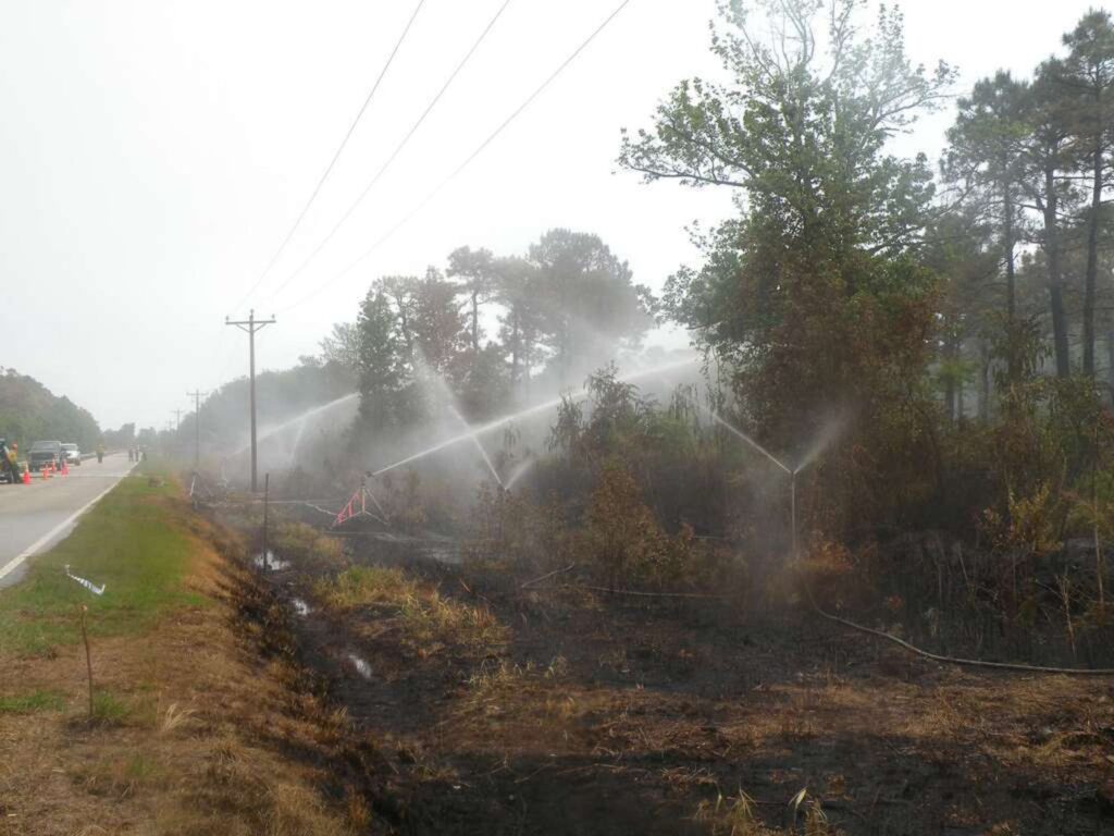 sprinklers extinguishing fire next to highway