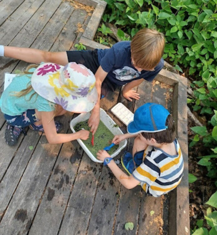 children on an outdoor deck gathering around an activity.
