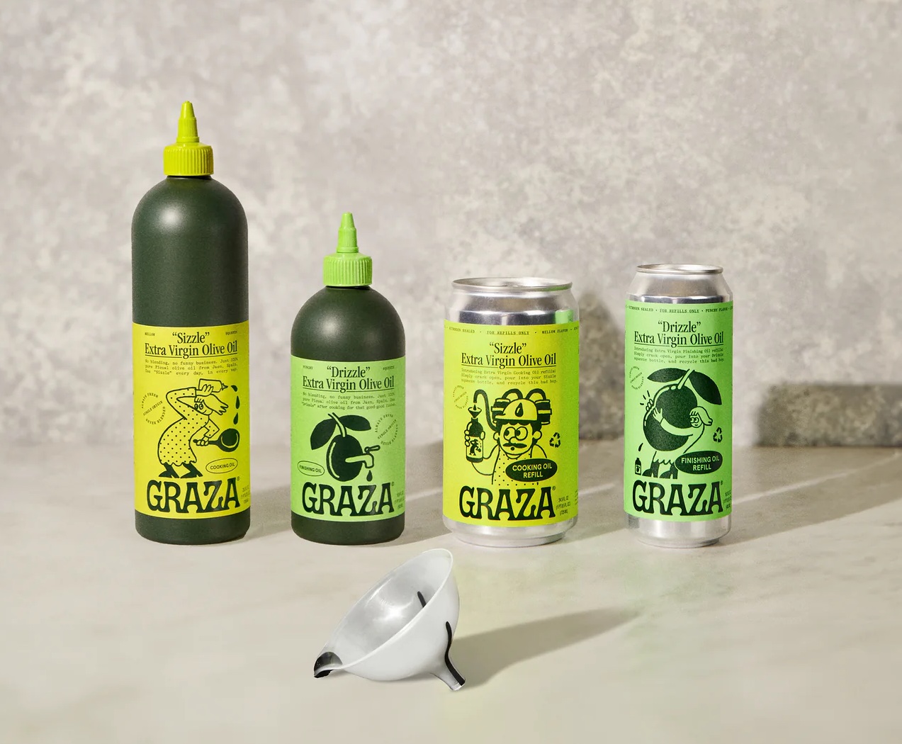 Two dark green bottles of Graza olive oil and two refill cans of olive oil, with a clear plastic funnel.