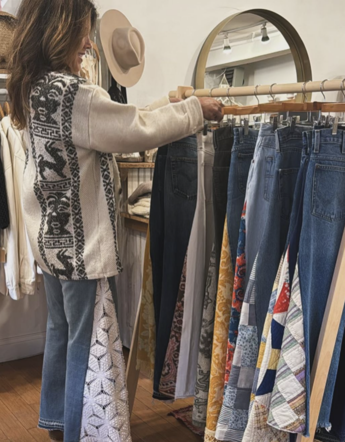 a woman looking at a rack of jeans