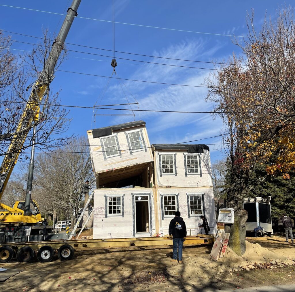 a crane carefully places puts together a house