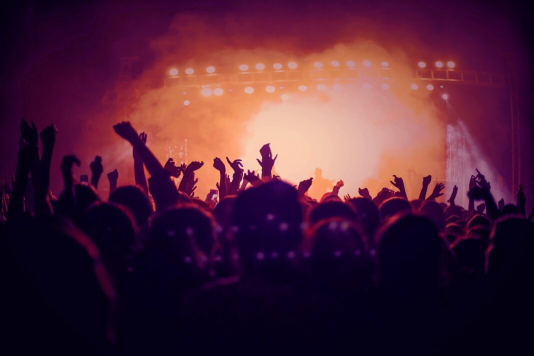 People with their hands up in front of a concert stage.
