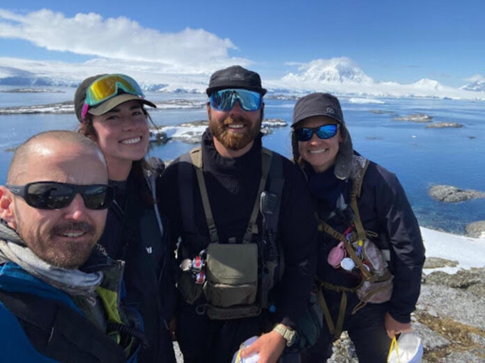 people standing on hill with ocean in background