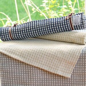 A pile of cotton rugs on a small table in a sunny room.
