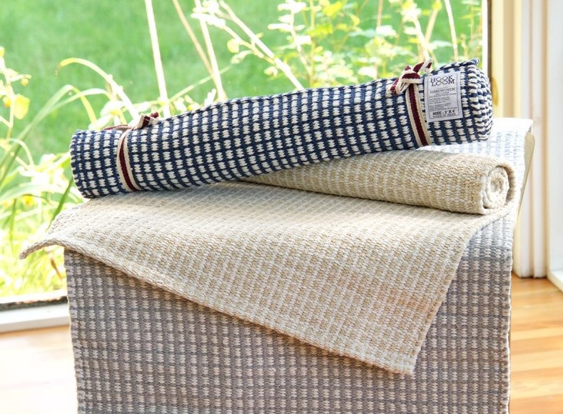 A pile of cotton rugs on a small table in a sunny room.
