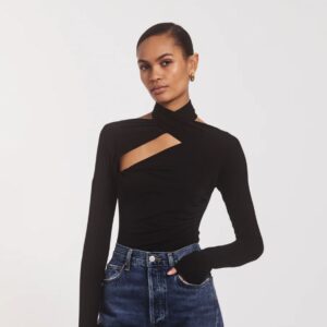 A woman wearing a long-sleeved black top with cutouts on the collarbone.