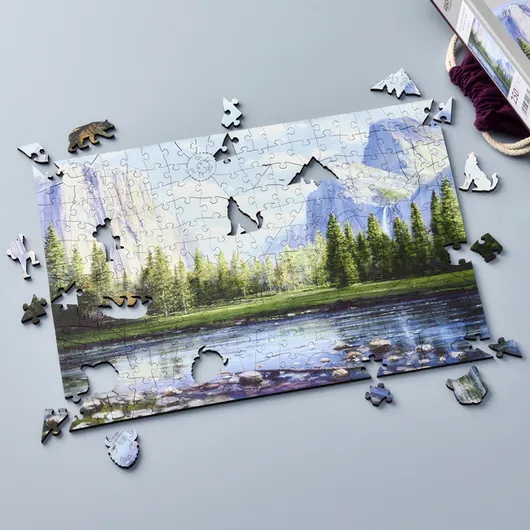 a nearly complete puzzle of a snowy mountains behind green pine trees and a blue lake.