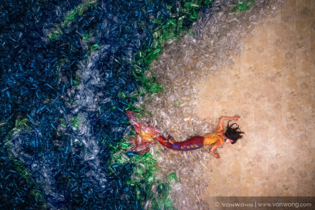 A mermaid lays in a sea of plastic