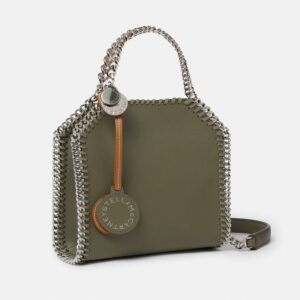 A small olive green purse with a silver chain strap and a round silver keychain with the words Stella McCartney printed on it.