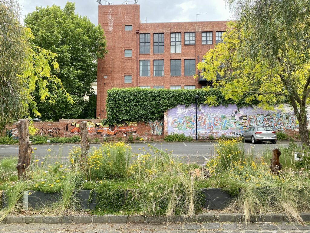 A brick building with lots of lush greenery around it.