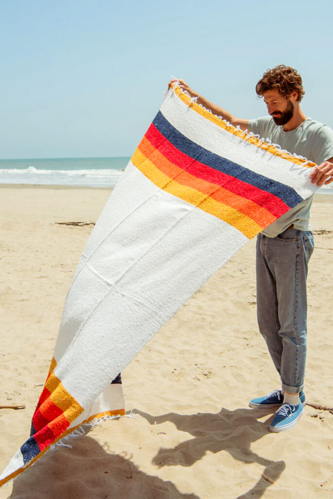 a person with colorful striped blanket on the beach
