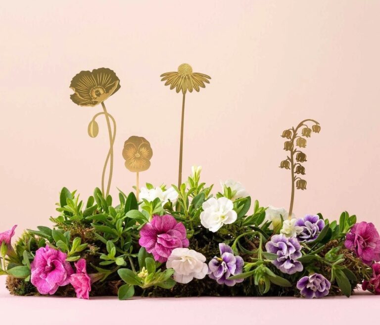 A live flower arrangement with small decorative brass flowers sticking up out of it.