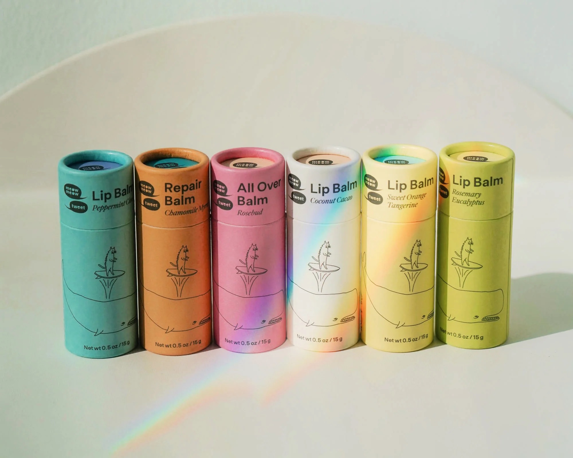 Six colorful cardboard tubes of lip balm and body balm from the brand Meow Meow Tweet.