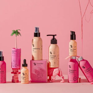 An assortment of Meow Meow Tweet brand products for face and body, all packaged in bright and light pink metal bottles and cardboard tubes.