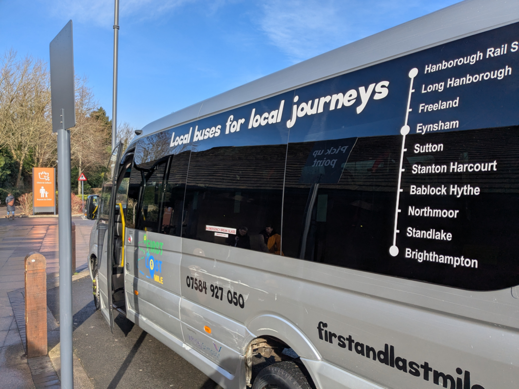 A slanted view of the silver community bus with the map of the stops printed on the window.