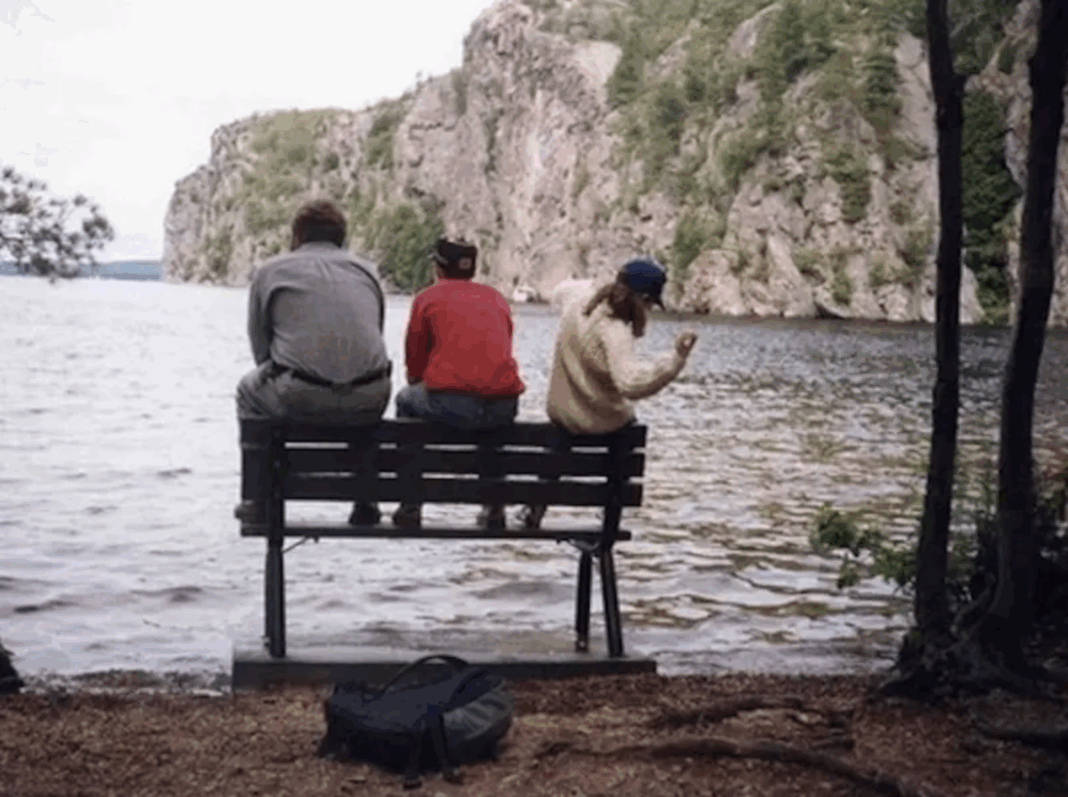 a family sits on a bench overlooking a lake