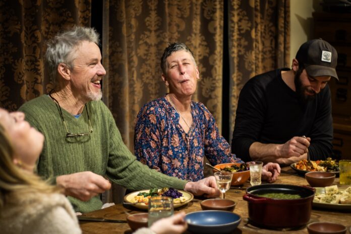 people sitting at dinner table laughing and eating