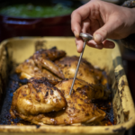 roasted chicken with person checking with meat thermometer